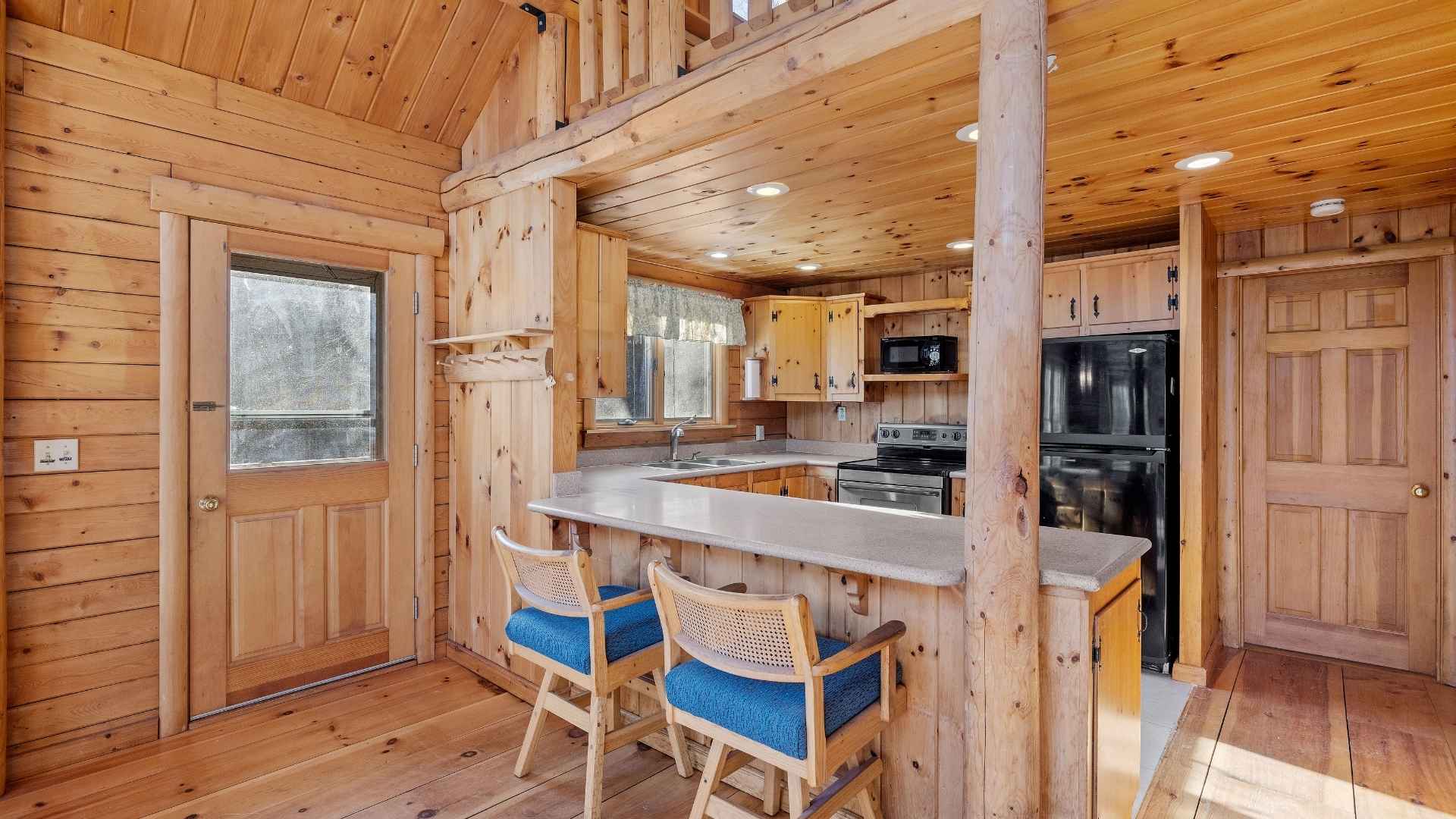A cozy, impeccably clean cabin living room with wooden beams and a stone fireplace in Gatlinburg.